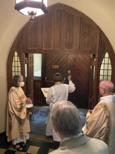 Rector blessing doors with Holy Water